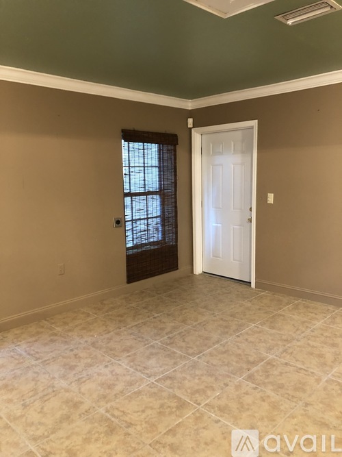 A room with a door and a window with a view of trees.
