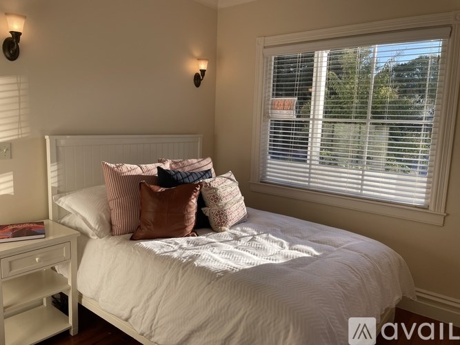 A bedroom with a bed, nightstand, and window with blinds.