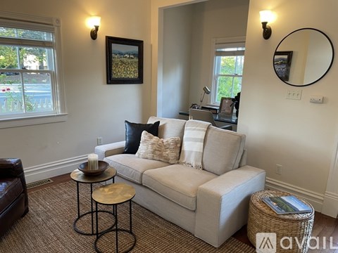 A living room with a couch, a table, and a painting on the wall.