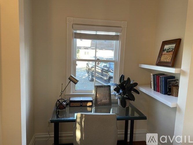 A table with a lamp and a plant on it in front of a window.