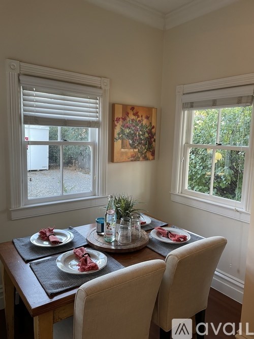A dining table set with plates and cutlery is in front of a window.
