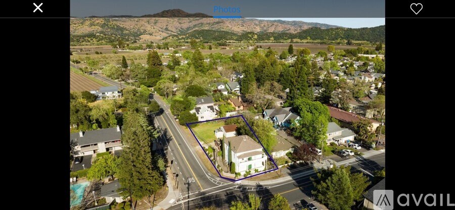 A bird's eye view of a residential area with a house in the foreground and a mountain in the distance.