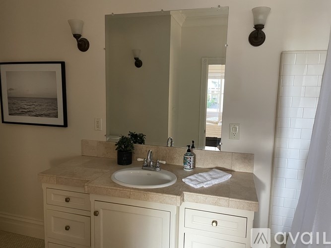 A bathroom with a sink, mirror, and a picture on the wall.