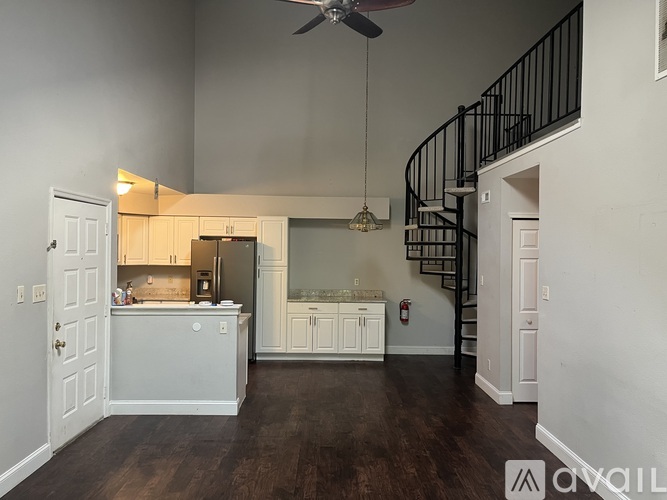 A kitchen with a spiral staircase in the background.