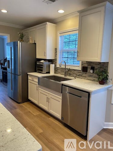 A kitchen with a refrigerator, sink, and cabinets.