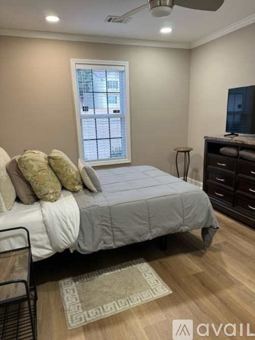 A bedroom with a bed, a window, and a rug.