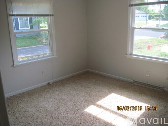 A room with a carpeted floor and two windows, one of which is open.