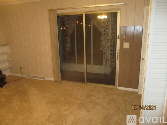 A room with a carpeted floor and a sliding glass door.