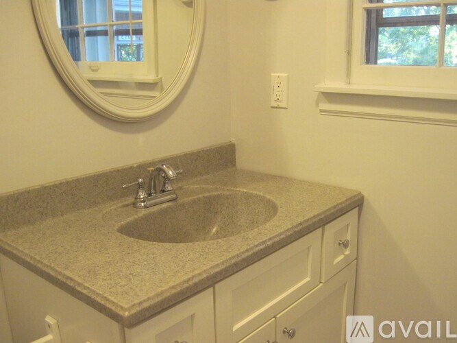 A bathroom with a granite countertop and a round mirror.
