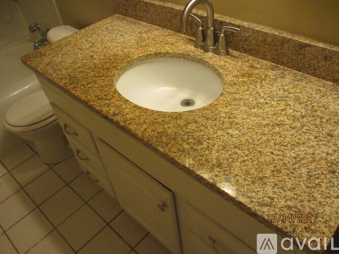 A bathroom with a granite countertop and a white sink.