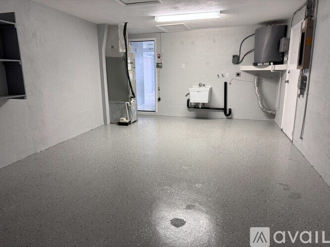 A spacious, empty room with a concrete floor and white walls.