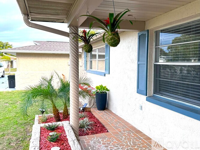 A house with a red brick walkway and a potted plant on the porch.