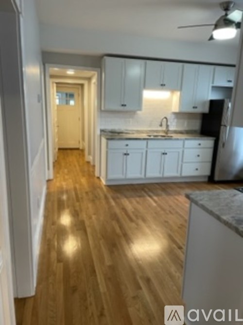 A kitchen with white cabinets and a wooden floor.