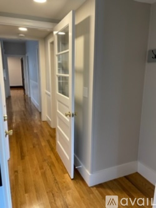 A hallway with wood floors and white walls.