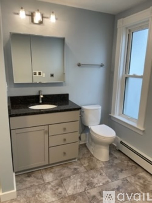 A bathroom with a sink, toilet and mirror.