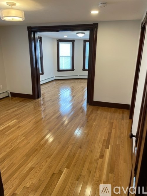 A room with wooden flooring and a doorway leading to another room.
