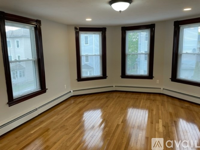 A room with wooden floors and three windows.