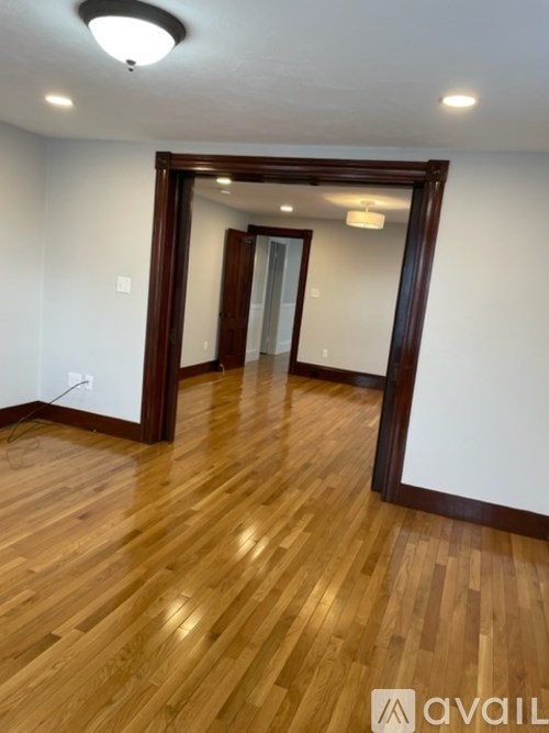 A room with wooden flooring and a mirrored doorway.