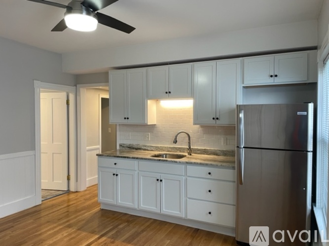 A kitchen with white cabinets and a stainless steel refrigerator.