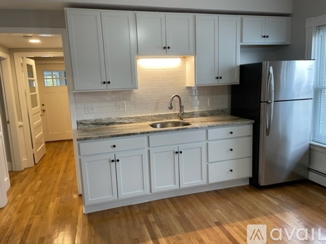 A kitchen with white cabinets and a black refrigerator.