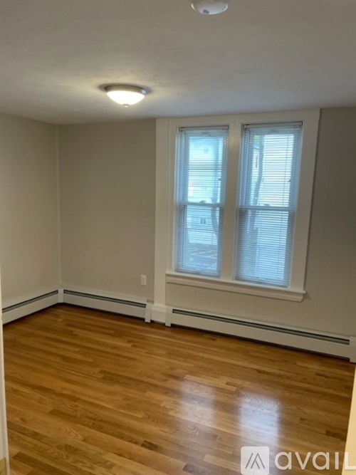 A room with wooden flooring and a window with blinds.