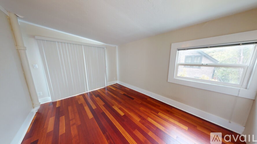 A room with wooden flooring and a window.