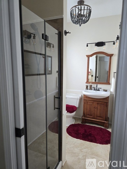 A bathroom with a sink, mirror, and shower.