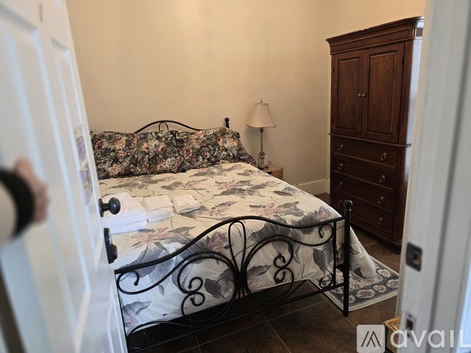 A bedroom with a floral bedspread and a wooden cabinet.
