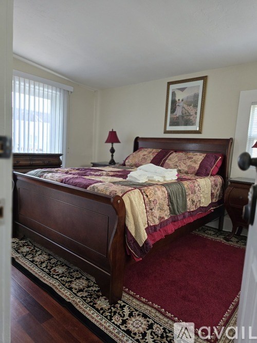 A bedroom with a large bed and a rug on the floor.