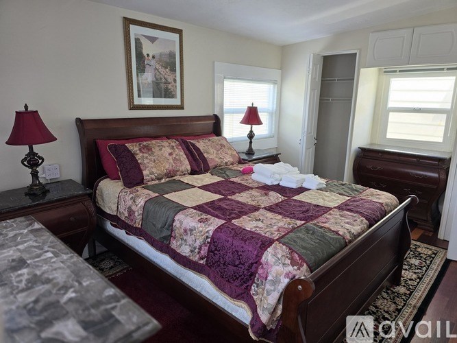 A bedroom with a large bed and a painting on the wall.