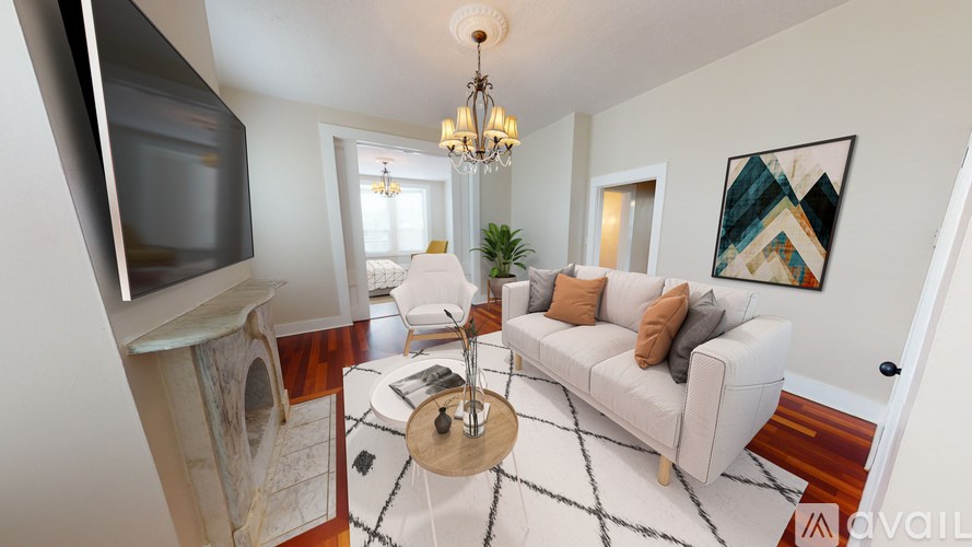 A living room with a white couch, a coffee table, a television, and a chandelier.