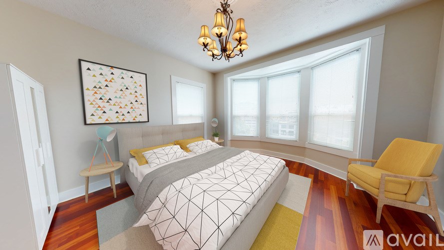 A bedroom with a bed, a chair, and a chandelier.