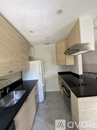A kitchen with wooden cabinets and black countertops.
