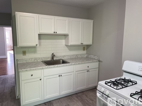 A kitchen with white cabinets and a white gas stove.