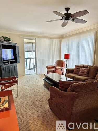 A living room with a television, couch, and chairs.