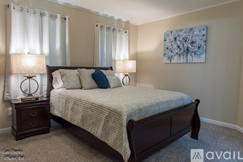 A bedroom with a large bed and two lamps.