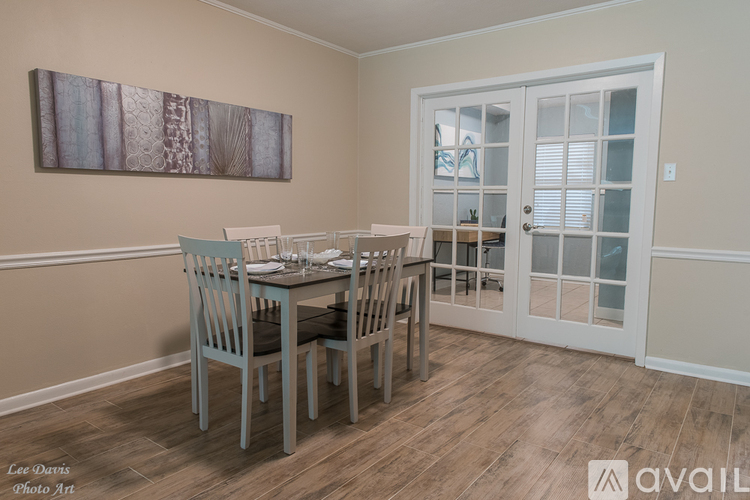 A dining room with a table set for two and a painting on the wall.