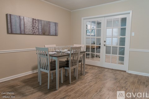 A dining room with a table set for two and a painting on the wall.