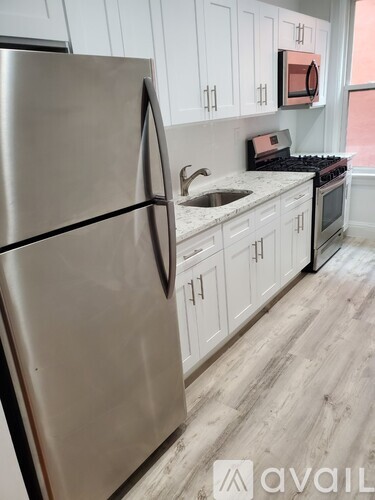 A kitchen with a stainless steel refrigerator and white cabinets.