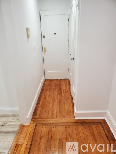 A hallway with a wooden floor and white walls.
