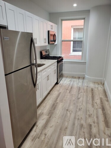 A kitchen with a stainless steel refrigerator and wooden flooring.