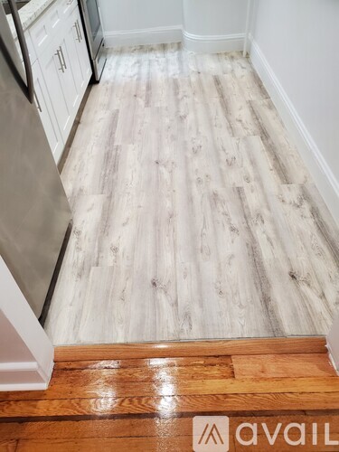 A kitchen with a white fridge and wooden flooring.
