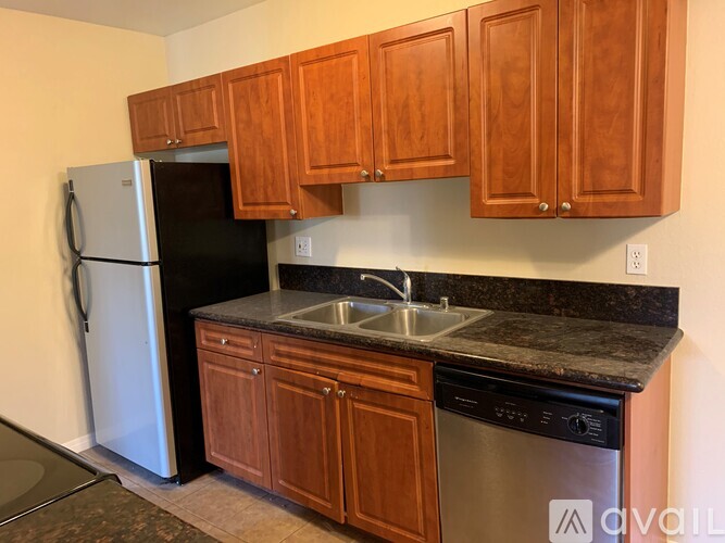 A kitchen with wooden cabinets and a black fridge.