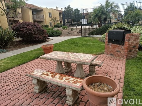 A brick picnic table with a matching bench in front of a building.
