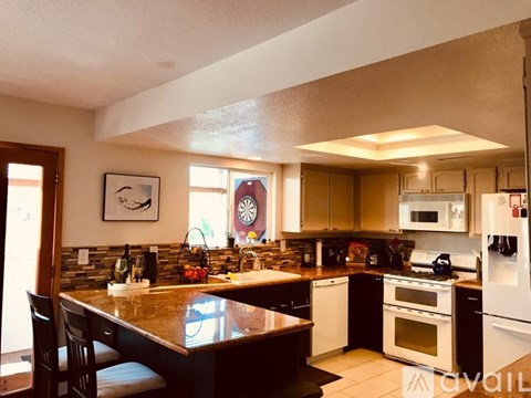 A kitchen with a brown counter top and white appliances.