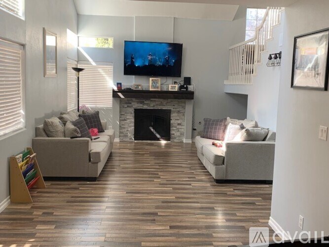A living room with a fireplace and a television on the wall.