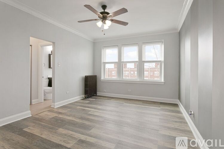 A spacious room with a ceiling fan and a radiator.