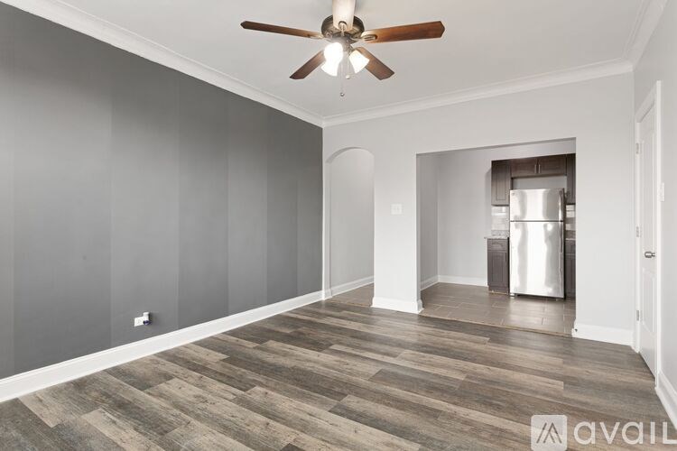 A room with a ceiling fan and wooden flooring.