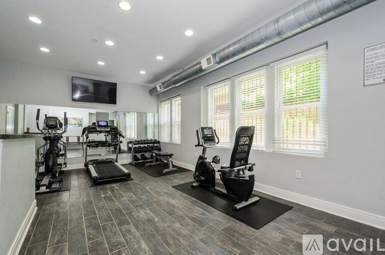 A well-lit home gym with a variety of exercise equipment.