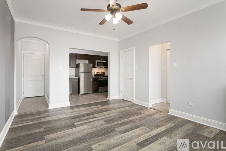 A spacious room with a ceiling fan and a kitchen area in the background.